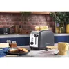 A kitchen counter scene with a toaster, bread, butter, jam, and a mug. Voir les images du produit