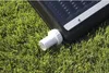 A close-up of a black solar collector with a white fitting attached, resting on green grass. Podgląd zdjęcia produktu