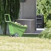 A green wheelbarrow filled with wood sits in front of a tan storage box and a black compost bin, with trees and grass in the background. Produktbild-Vorschau