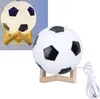 A soccer ball shaped lamp on a wooden stand, with a power cord visible. Produktbild-Vorschau