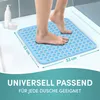 A person's feet are stepping onto a light blue, square shower mat with a textured surface, placed in a shower stall. There are also bottles of toiletries in the background. Produktbild-Vorschau