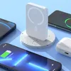 A white magnetic power bank is displayed on a textured circular stand, surrounded by smartphones and a charging case, suggesting a modern tech setup. Produktbild-Vorschau