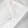 A close-up view of white sheer curtains with embroidered floral patterns. Produktbild-Vorschau