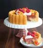 A cake on a cake stand with a slice on a plate. Produktbild-Vorschau