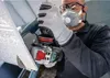 A person wearing protective gear is using a power tool to cut a piece of material. Voir les images du produit