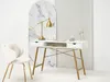 A white desk with golden legs, a golden lamp, and a chair in a modern setting. Voir les images du produit