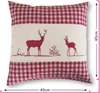 A square cushion with a red and white gingham pattern on the top and bottom, and a cream-colored band in the middle featuring two red deer silhouettes. Produktbild-Vorschau