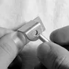 Hands holding a metal screw and a metal bracket with a hole. Anteprima dell’immagine prodotto