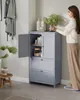 A woman is placing a bouquet of flowers into a gray bathroom cabinet. Produktbild-Vorschau