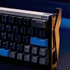 A close-up view of a mechanical keyboard with a black, white, and gold color scheme. Produktbild-Vorschau