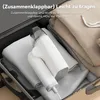 A white garment steamer is shown placed inside a suitcase on top of folded clothes. Produktbild-Vorschau