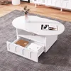 A white, cloud-shaped coffee table with a drawer and an open shelf, placed on a gray rug in a living room setting. Voir les images du produit
