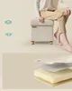 A person sitting on a storage ottoman, with layered diagrams showing the ottoman's construction. Produktbild-Vorschau