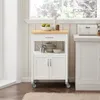 A white kitchen cart with a wooden top is shown in a kitchen setting, next to a window and a larger cabinet. Produktbild-Vorschau