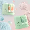 Two mint green baby food makers are shown against a pastel background with scoops of ice cream. Produktbild-Vorschau