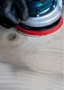 A close-up of a sander being used on a wooden surface. Produktbild-Vorschau