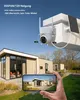 A security camera is mounted on a building, with a phone displaying a view of houses in the foreground. Produktbild-Vorschau
