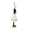 A side profile of a decorative figurine of a rabbit dressed in a black jacket, white skirt, and black boots, holding a gold purse. Náhľad obrázku produktu
