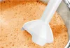 A close-up of an immersion blender in a container of orange liquid with foam. Náhľad obrázku produktu