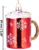 A close-up studio shot of a red glass Christmas ornament shaped like a mug with white frosting and colorful sprinkles on top, and white snowflakes on the mug. A golden glitter handle is attached to the side. A measurement scale is shown on the left side of Produktbild-Vorschau