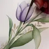 A close-up of a hand painting a watercolor tulip with glitter accents. Voir les images du produit