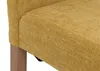 A close-up view of the textured yellow fabric of a chair, with a wooden leg visible on the left. Náhled obrázku produktu