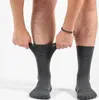 A person is putting on a pair of grey socks. Produktbild-Vorschau