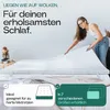A woman is placing a mattress topper on a bed. Produktbild-Vorschau