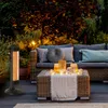 An outdoor patio scene at dusk, featuring a heater, sofa, and coffee table decorated with lights and candles. Anteprima dell’immagine prodotto