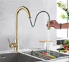 A person is using a gold kitchen faucet with a pull-out spray in a kitchen sink. Produktbild-Vorschau