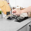 A hand is shown placing a glass lid on a gas stove in a kitchen setting. Produktbild-Vorschau