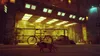 A cat wearing a backpack walks in front of a building with a bicycle parked outside. Produktbild-Vorschau