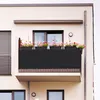 A balcony with a black privacy screen and potted flowers. Anteprima dell’immagine prodotto