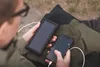 A person is holding a solar power bank and a smartphone, seemingly charging the phone with the power bank. Anteprima dell’immagine prodotto