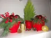 Christmas-themed decorations with red pots, pine branches, red ornaments, pinecones, and a small evergreen tree. Anteprima dell’immagine prodotto