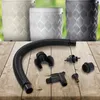 A collection of accessories for a rain barrel system, including a flexible hose, connectors, and a hole saw, are laid out on a wooden surface. In the background, three decorative rain barrels are visible. Náhled obrázku produktu