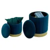 Two blue velvet storage ottomans with gold bases are shown against a white background. One ottoman is open, revealing a green pillow inside. The other ottoman is closed, with its lid resting beside it. Náhľad obrázku produktu