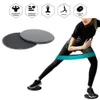 Zwei Core-Slider, einer dunkelgrau und einer hellgrau, neben einer Frau, die zwei dunkelgraue Slider für eine seitliche Ausfallschrittübung mit einem türkisen Widerstandsband verwendet Podgląd zdjęcia produktu