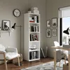 A white bookshelf filled with books and decorative items in a room with a chair, desk, and window. Anteprima dell’immagine prodotto