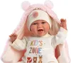 A close-up shot of a baby doll wearing a pink hooded blanket and a white outfit with colorful text and animal graphics. Podgląd zdjęcia produktu