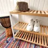 A shoe rack with a hat and shoes on it, next to a drum and a colorful rug. Podgląd zdjęcia produktu