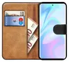 A book-style phone case with a smartphone inserted, showing cards and banknotes in the wallet section. Produktbild-Vorschau