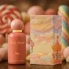 A perfume bottle and its box are displayed in front of a background of various candies and sweets. Produktbild-Vorschau