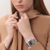 A woman wearing a tan jacket and a silver digital watch. Voir les images du produit