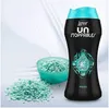 A bottle of Lenor Unstoppables and spilled beads on a white fabric background. Podgląd zdjęcia produktu