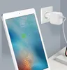 A white Apple iPad is charging next to a white Apple USB wall charger plugged into a white wall socket. Produktbild-Vorschau