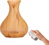 A hand holding a remote control is shown next to an aroma diffuser with a wood-like finish. Produktbild-Vorschau