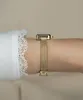 A close-up shot of a person's wrist wearing a gold watch. Voir les images du produit