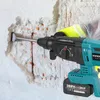 A close-up shot of a teal and black rotary hammer drill being used to break apart a concrete wall. Produktbild-Vorschau