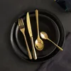 A set of gold cutlery is arranged on a black plate. Anteprima dell’immagine prodotto